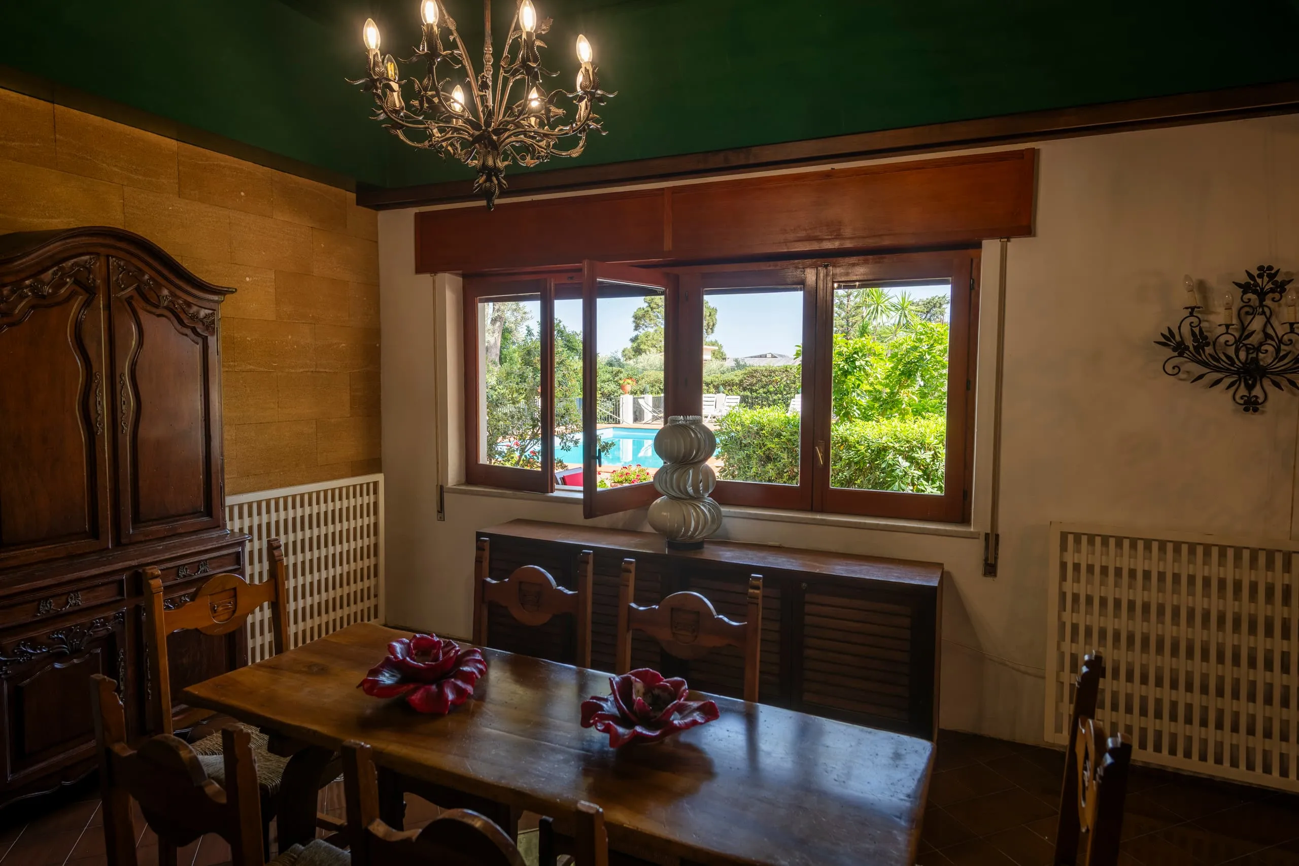 Sala da pranzo interna con tavolo in legno e finestra sulla piscina