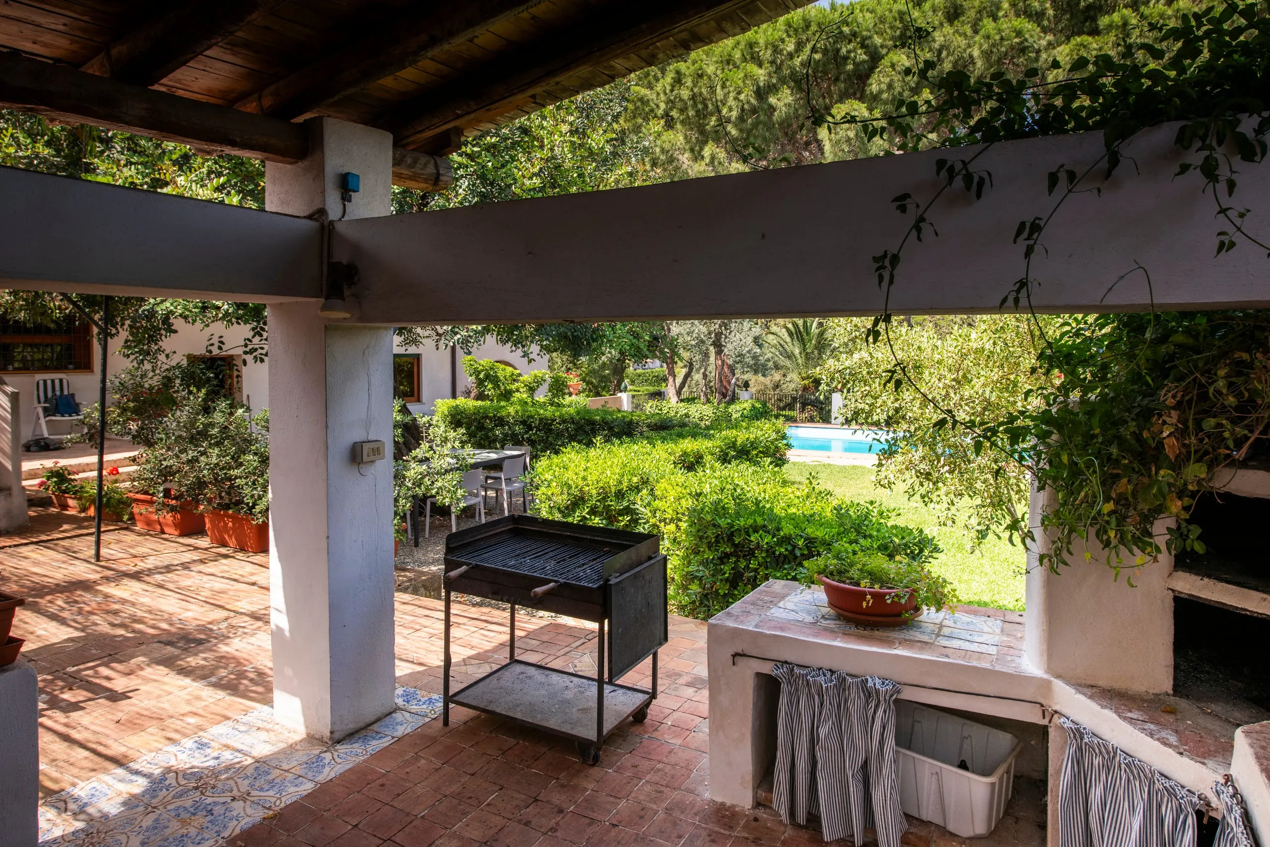 Porticato con barbecue affacciato sul giardino e sulla piscina