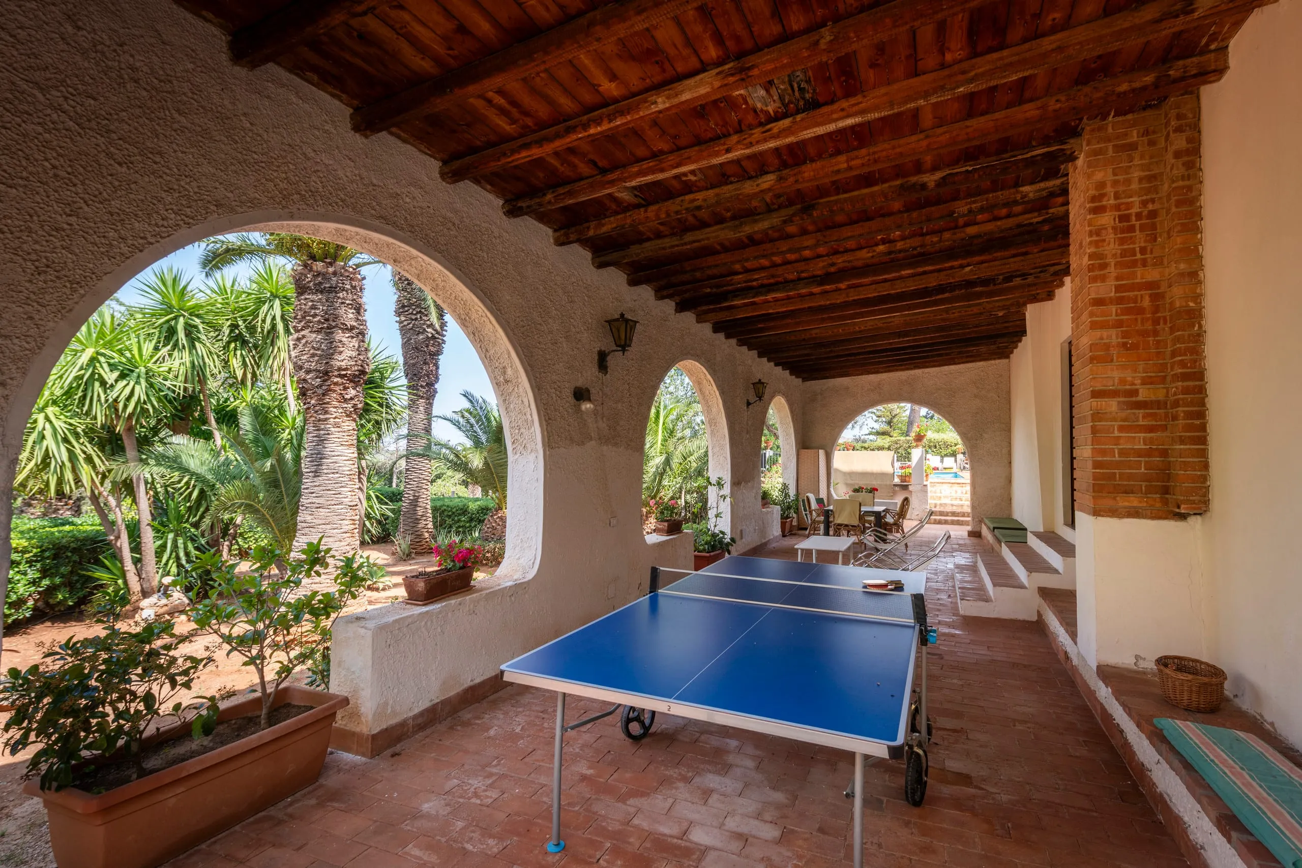 Tavolo da ping-pong sotto il porticato ad archi affacciato sulle palme