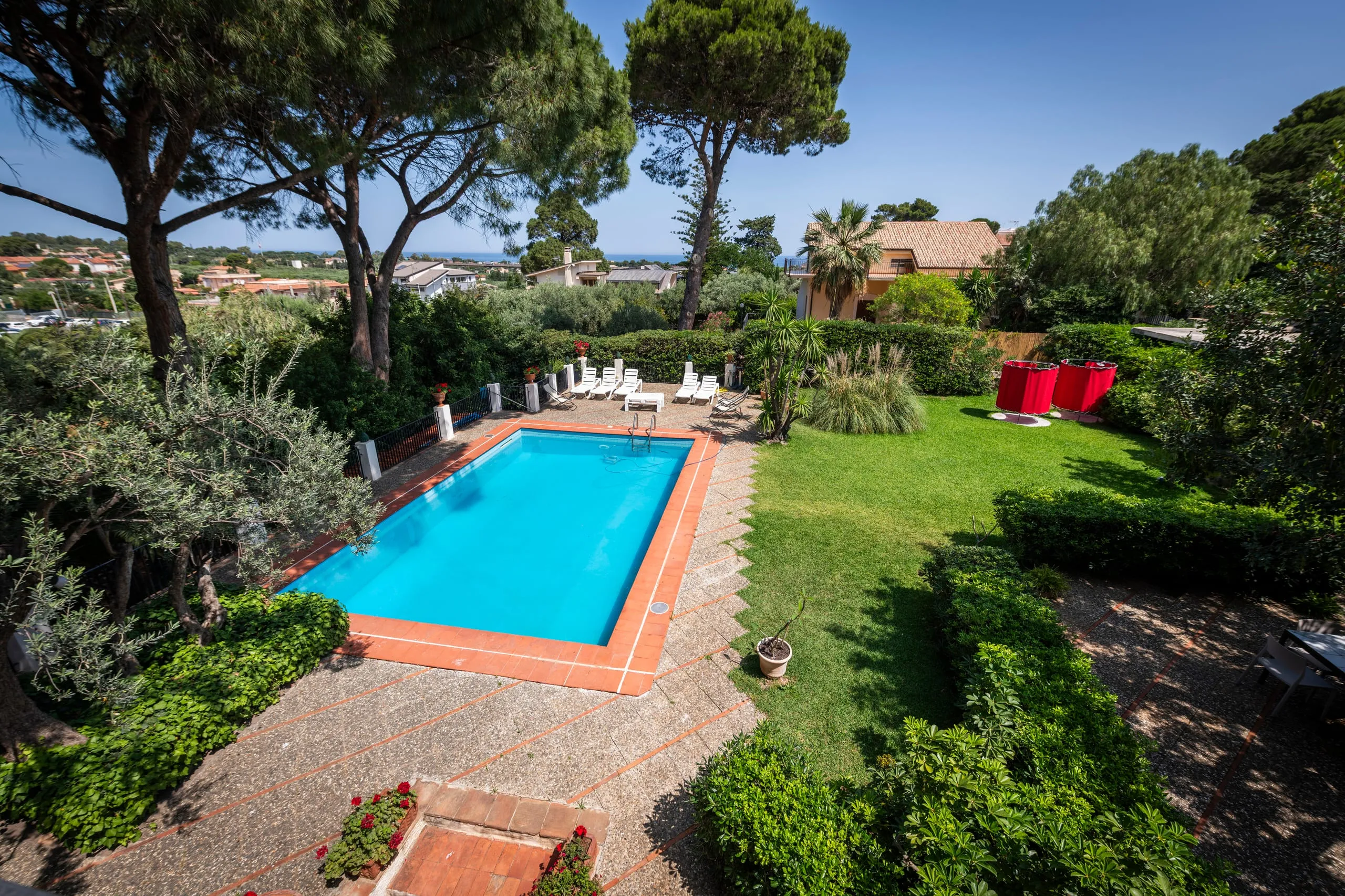 Vista dall’alto della piscina, del prato e del mare all’orizzonte