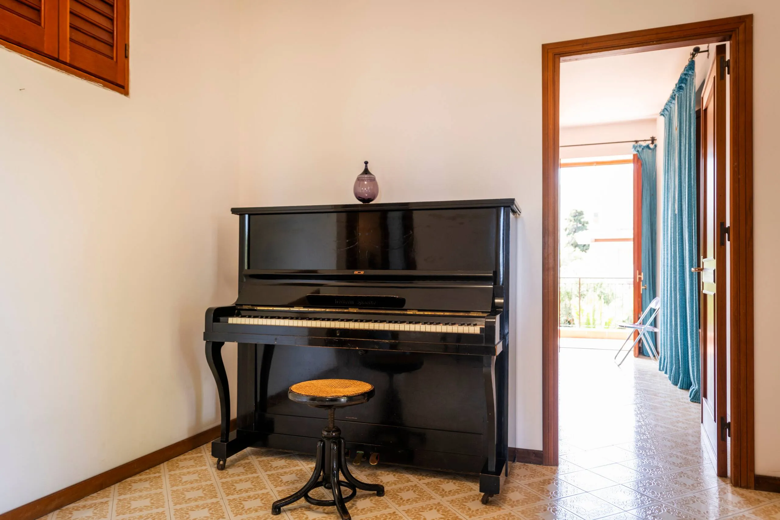 Pianoforte verticale nero con sgabello e pavimento in maioliche