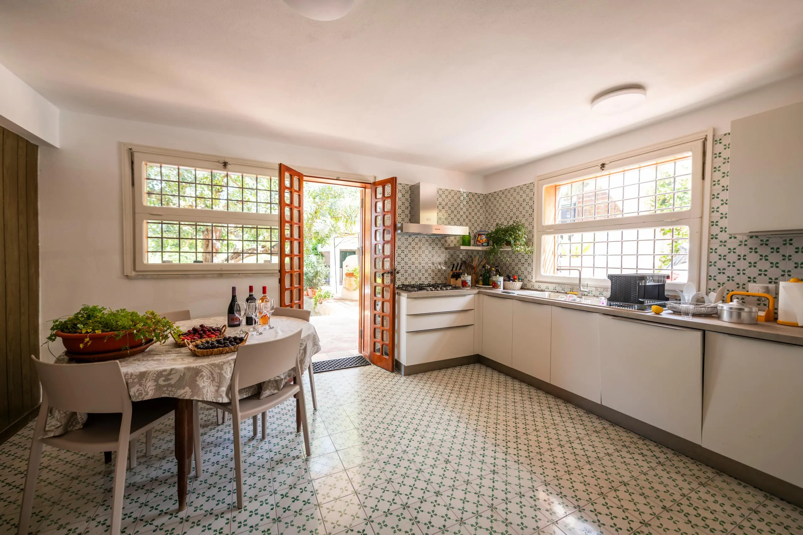 Cucina abitabile con tavolo e porta-finestra aperta sul giardino