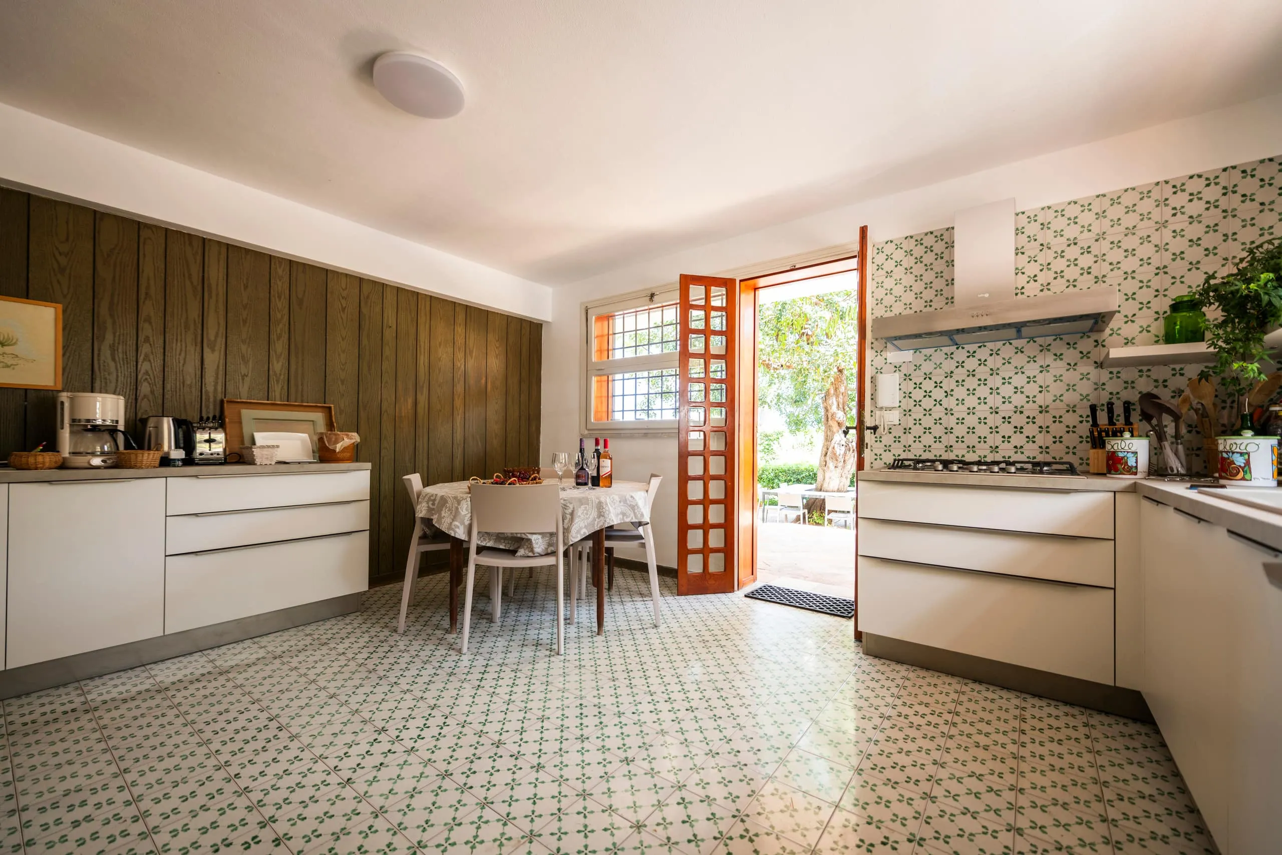 Cucina attrezzata con piano cottura, cappa e pavimento in cementine verdi